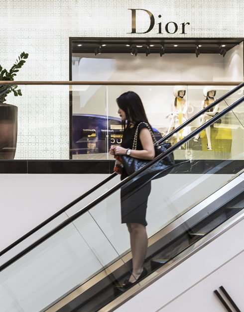 Women Going down in the escalator with Dior Store behind